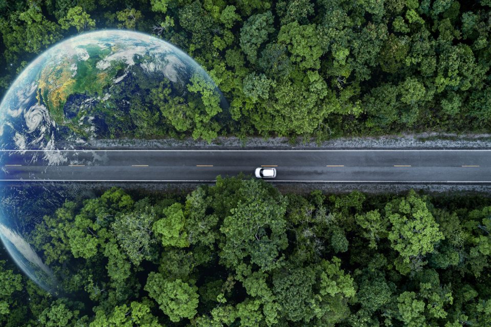 EVIG - Sicht von oben auf ein Auto, welches auf einer Straße durch einen Wald fährt, eine Reflexion unseres Planeten ist sichtbar